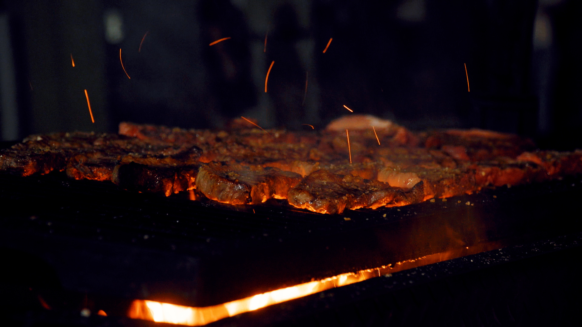 Picanha sizzling on grill with dramatic flames